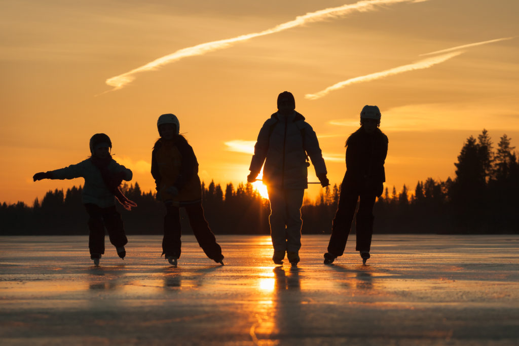 Family ice skating on frozen lake in winter
