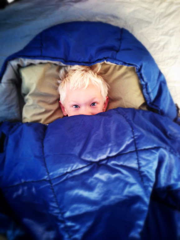 Kid snuggled up in sleeping bag of tent