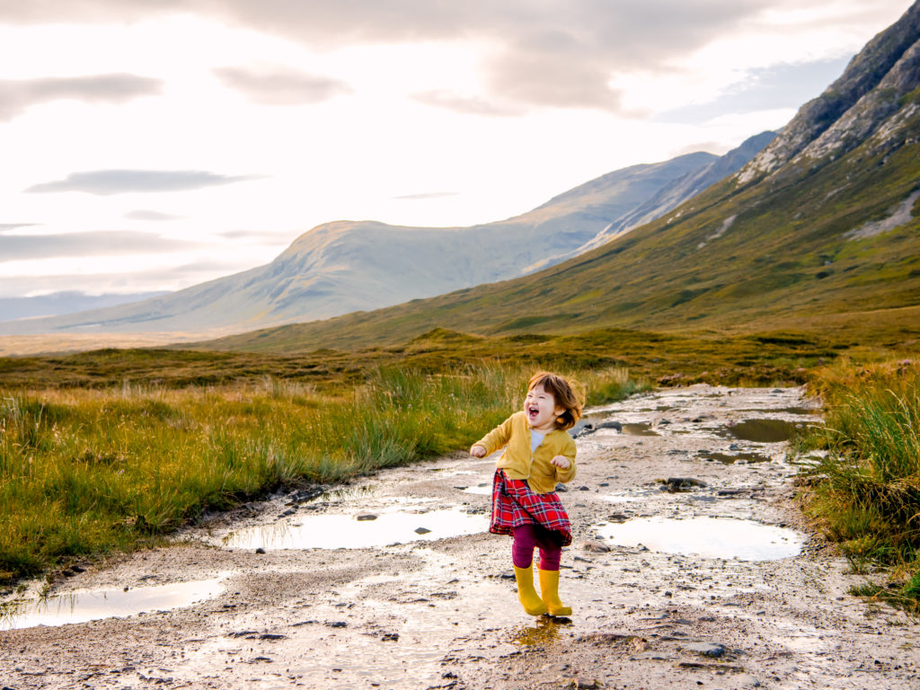 Child playing in puddles in Glencoe, Scotland