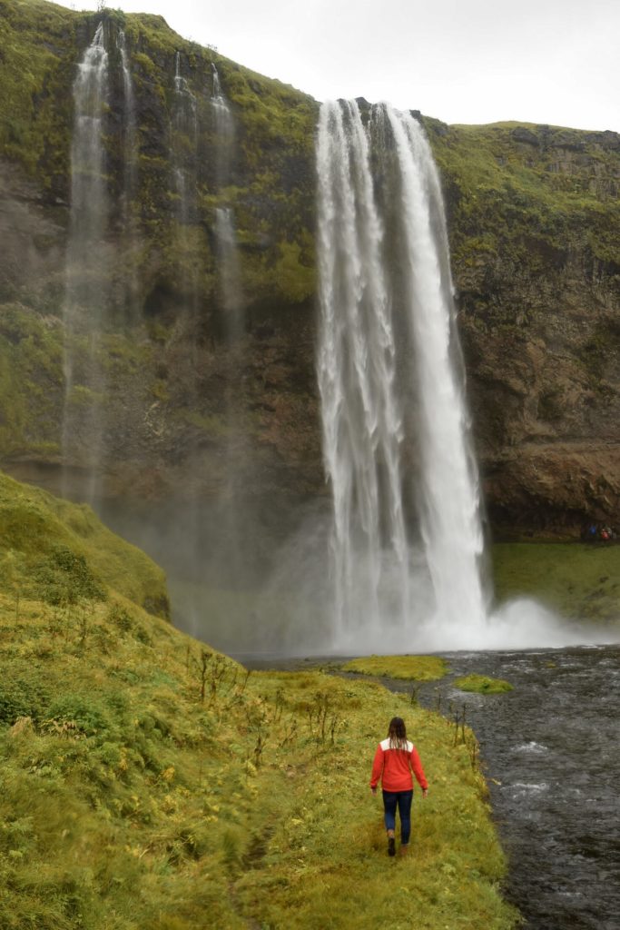 Woman walking towards Seljalandsfoss waterfall, Iceland