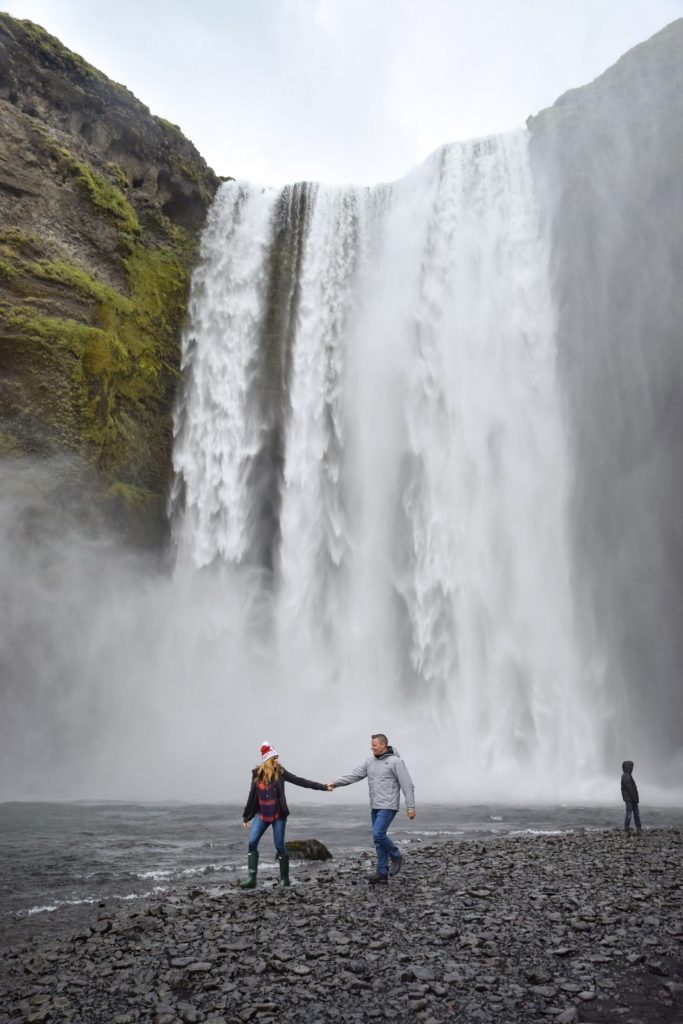 Couple walking in front of Skogafoss, Iceland