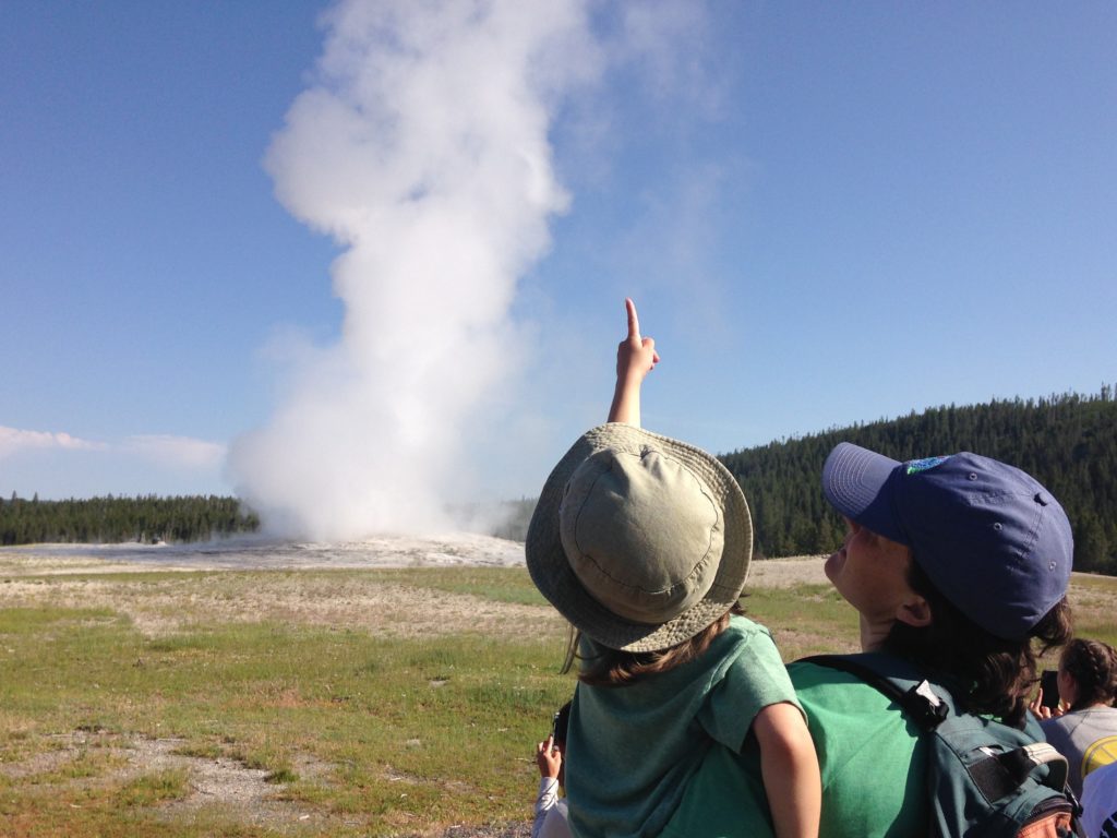 Mom and daughter watch an eruption of the Old Faithful in Yellowstone National Park, WY
