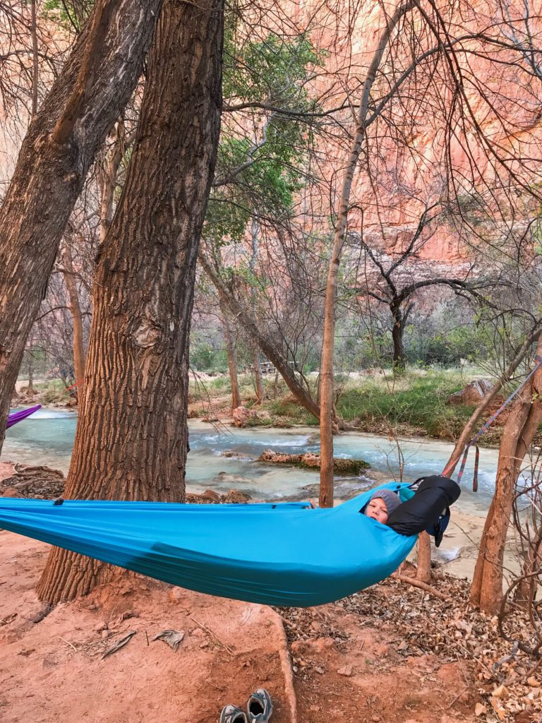 Kid sleeping in hammock near creek at campground in Havasupai, Arizona