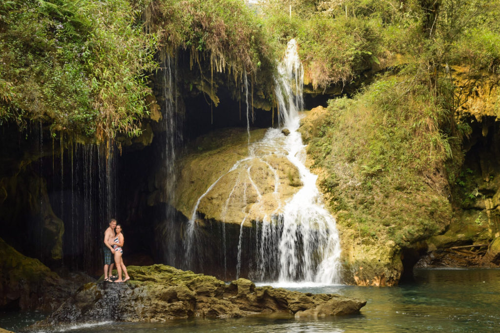 Couple standing on rocks at waterfall in Semuc Champey, Lanquin, Guatemala