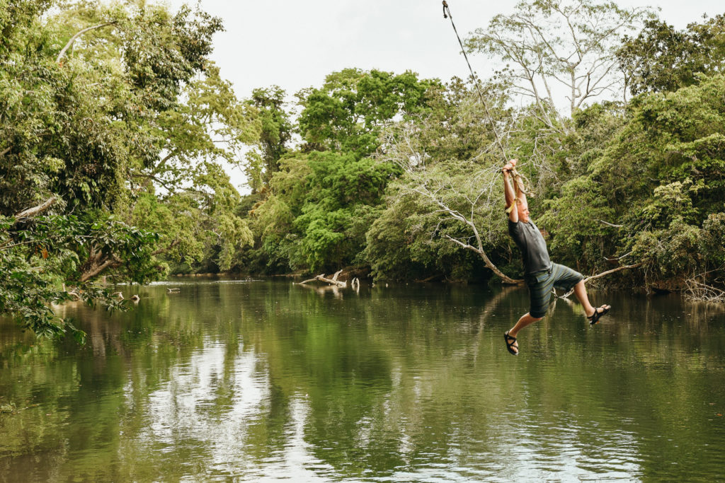 Jumping off rope swing at Mopan River, San Ignacio, Belize