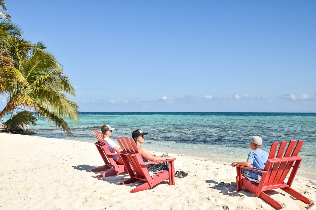 Family sitting on beach in Ranguana Caye, Belize