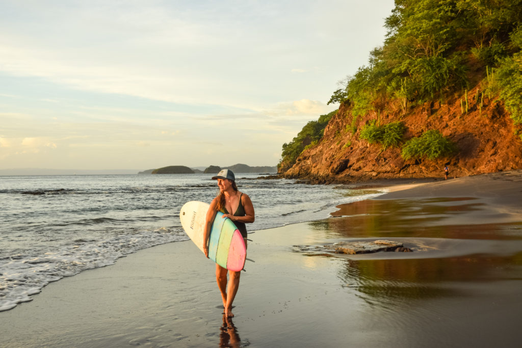 Golden hour at Playa Ocotal, surfer girl walking down beach, Costa Rica