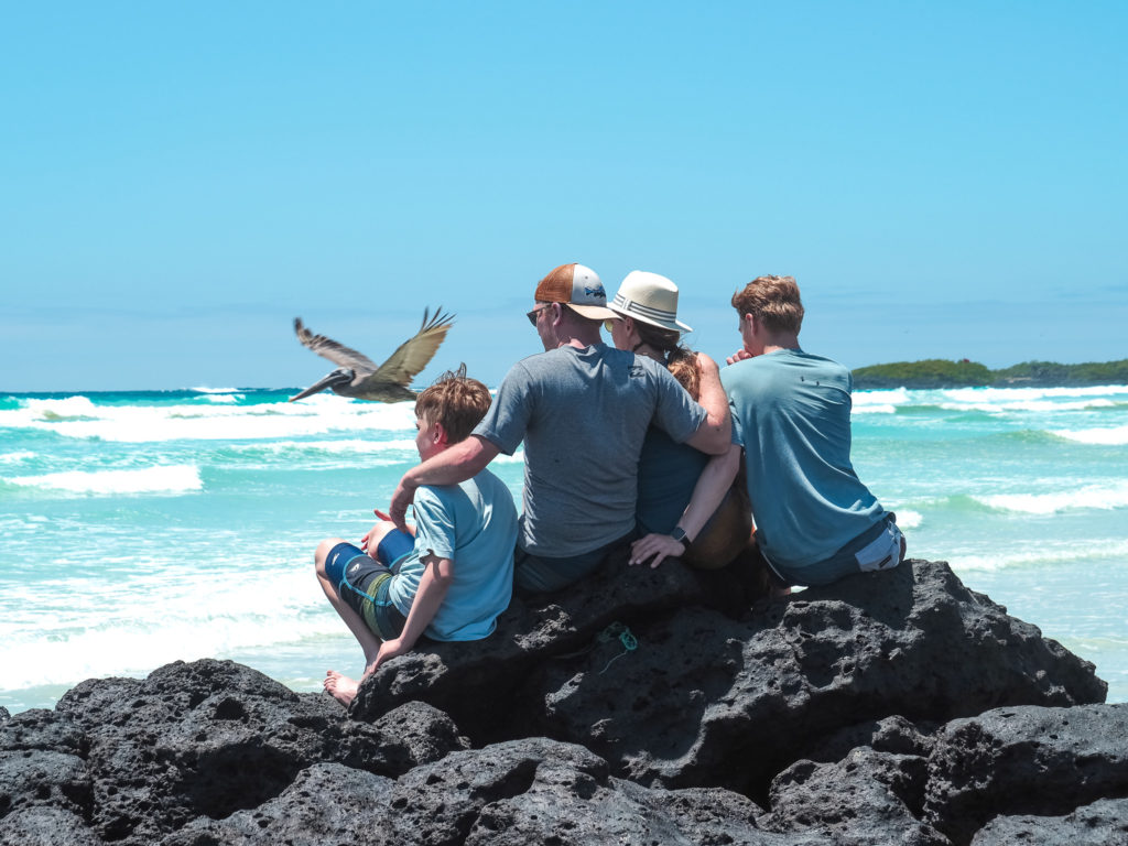 Family sitting on rocks overlooking Tortuga Bay, Santa Cruz, Galapagos, Ecuador