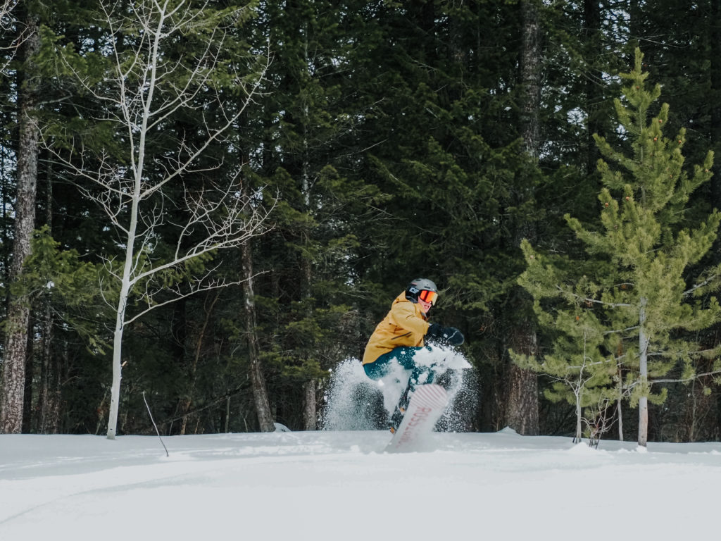 Snowboarding riding through powder at Kelly Canyon Ski Resort in Idaho
